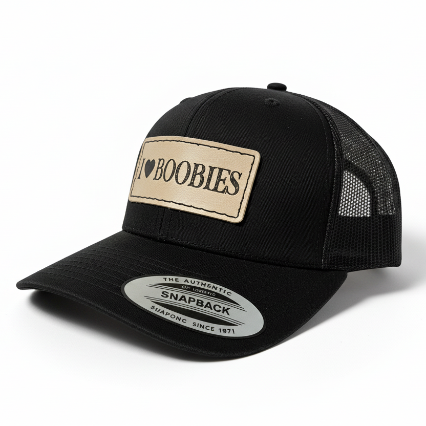 Black trucker cap with a tan patch displaying 'I ❤️ Boobies' on a white background