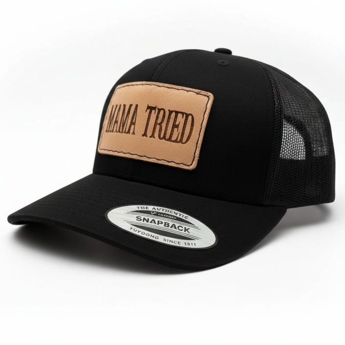 Black trucker cap with a brown leather patch and 'MAMA TRIED' text on a light gray background.