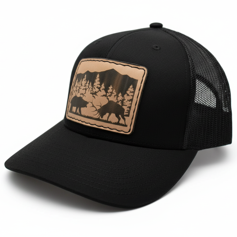Black trucker cap with a tan leather patch featuring a bear and mountain design on a white background