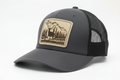 Gray trucker cap with a bear and forest design patch on a white background
