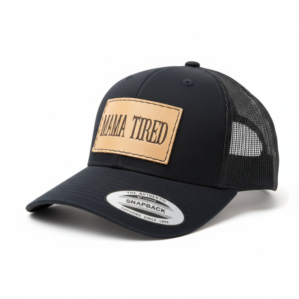 Black cap with 'MAMA TIRED' patch on a brown textured background