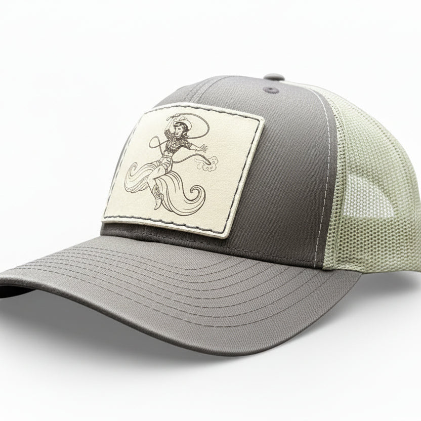 brown trucker hat with a decorative leather patch featuring a woman riding a moustache.