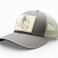 brown trucker hat with a decorative leather patch featuring a woman riding a moustache.