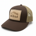 Brown and beige cap with a mountain and forest design on a white background