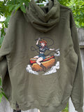 Green hoodie with a graphic design of a person on a hot dog, hanging on a wooden fence with greenery in the background.