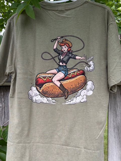 Green t-shirt with a graphic design of a woman on a hot dog against a wooden fence background
