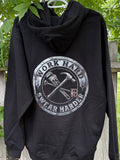 Black hoodie with 'Work Hard, Swear Harder' graphic on a wooden fence with greenery.